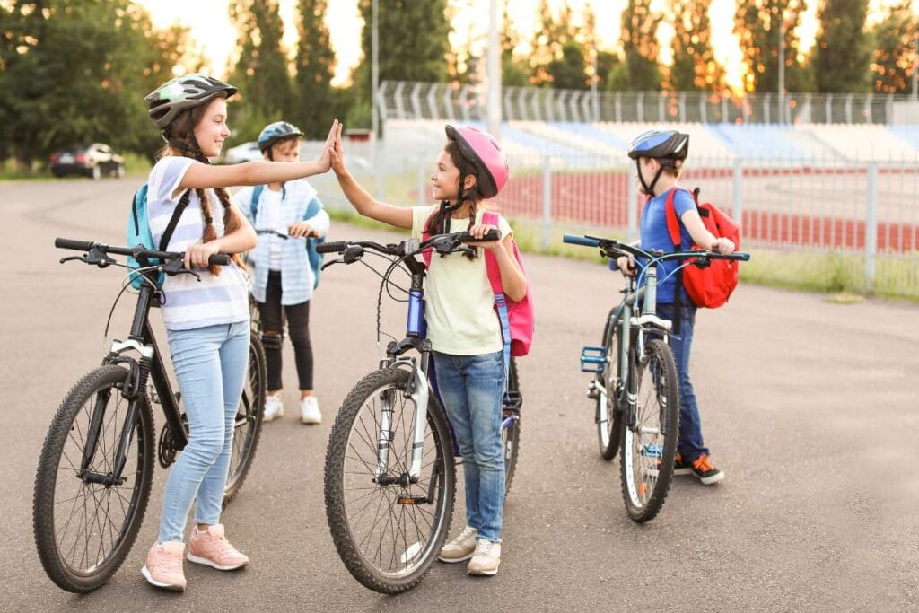 Happy kids with helmets high-fiving on bikes, enjoying a safe family day trip.