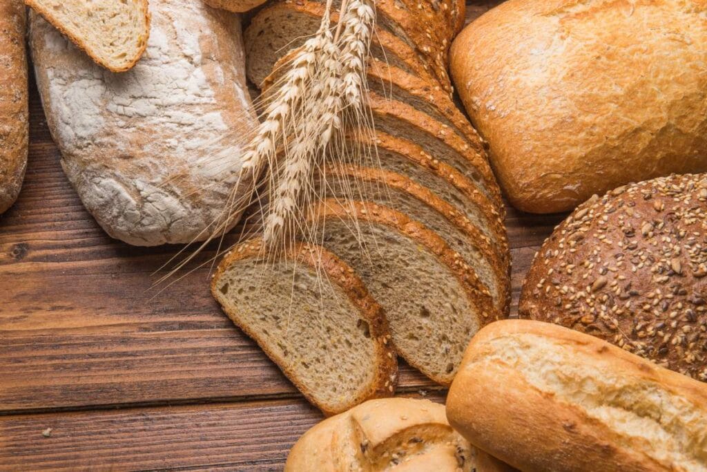 Fresh Italian bread loaves and slices on a wooden table.