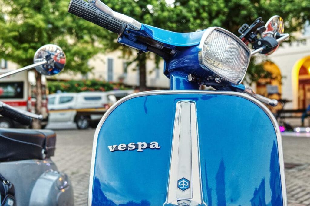 Classic red Vespa scooter parked on a Roman street, representing an exciting tour activity for teenagers