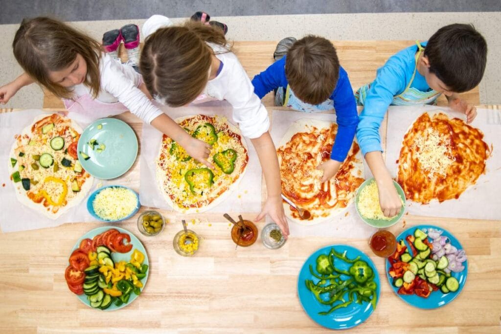 Top view of young children making homemade pizza during a family-friendly cooking class in Rome