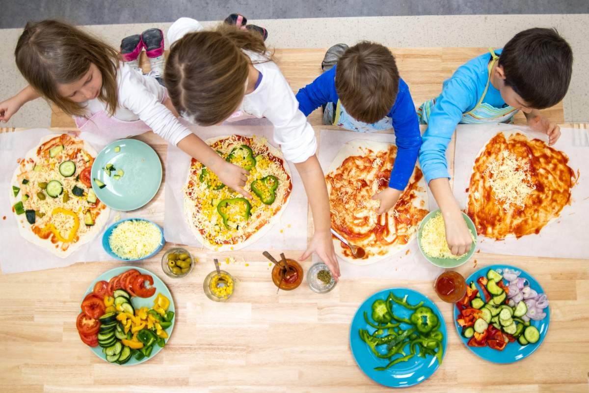 Top view of young children making homemade pizza during a family-friendly cooking class in Rome